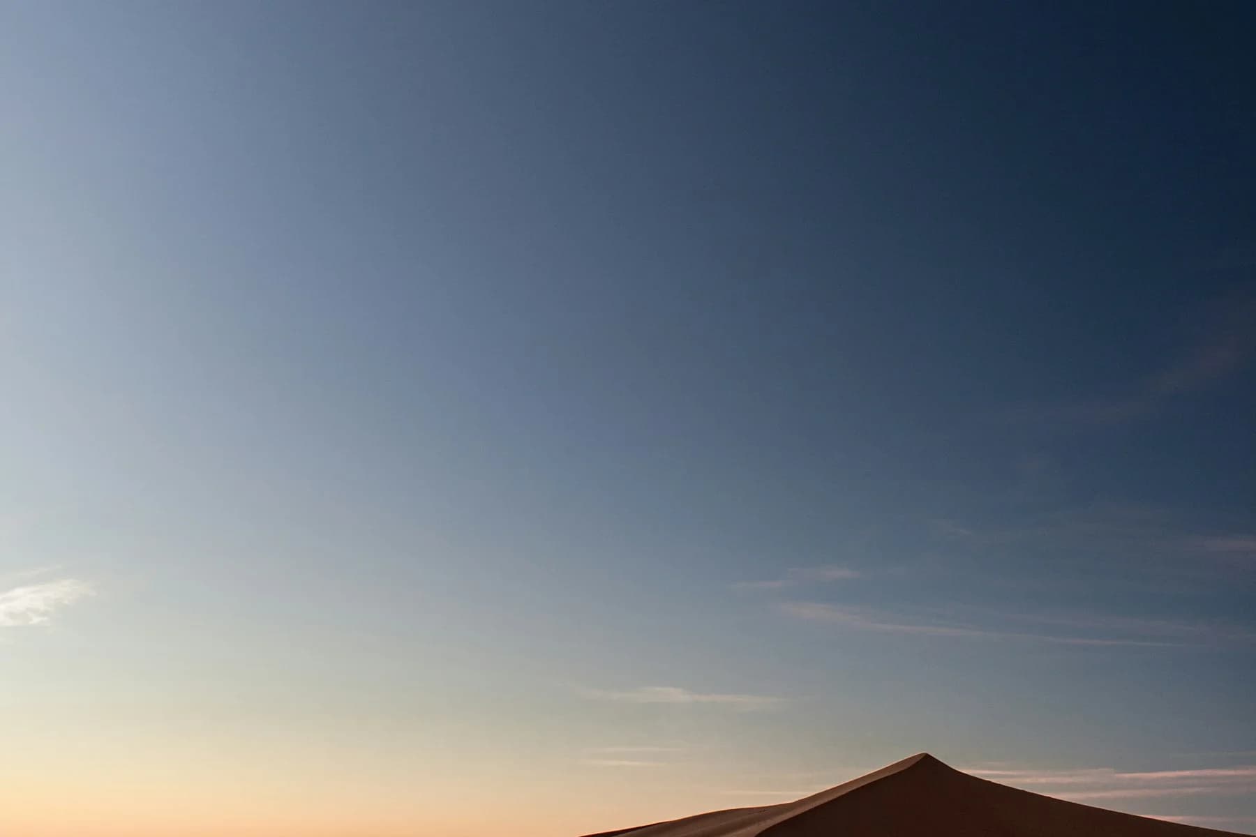 A dark desert ridge beneath a deep blue sky