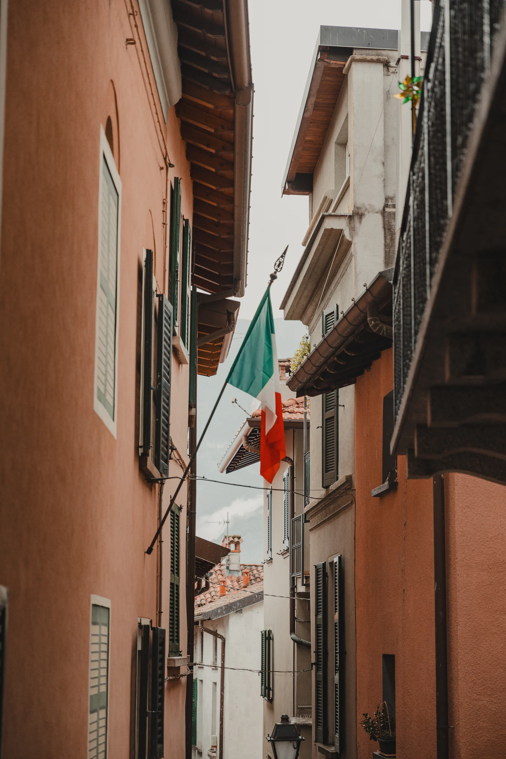 An Italian flag hanging in a narrow terracotta street