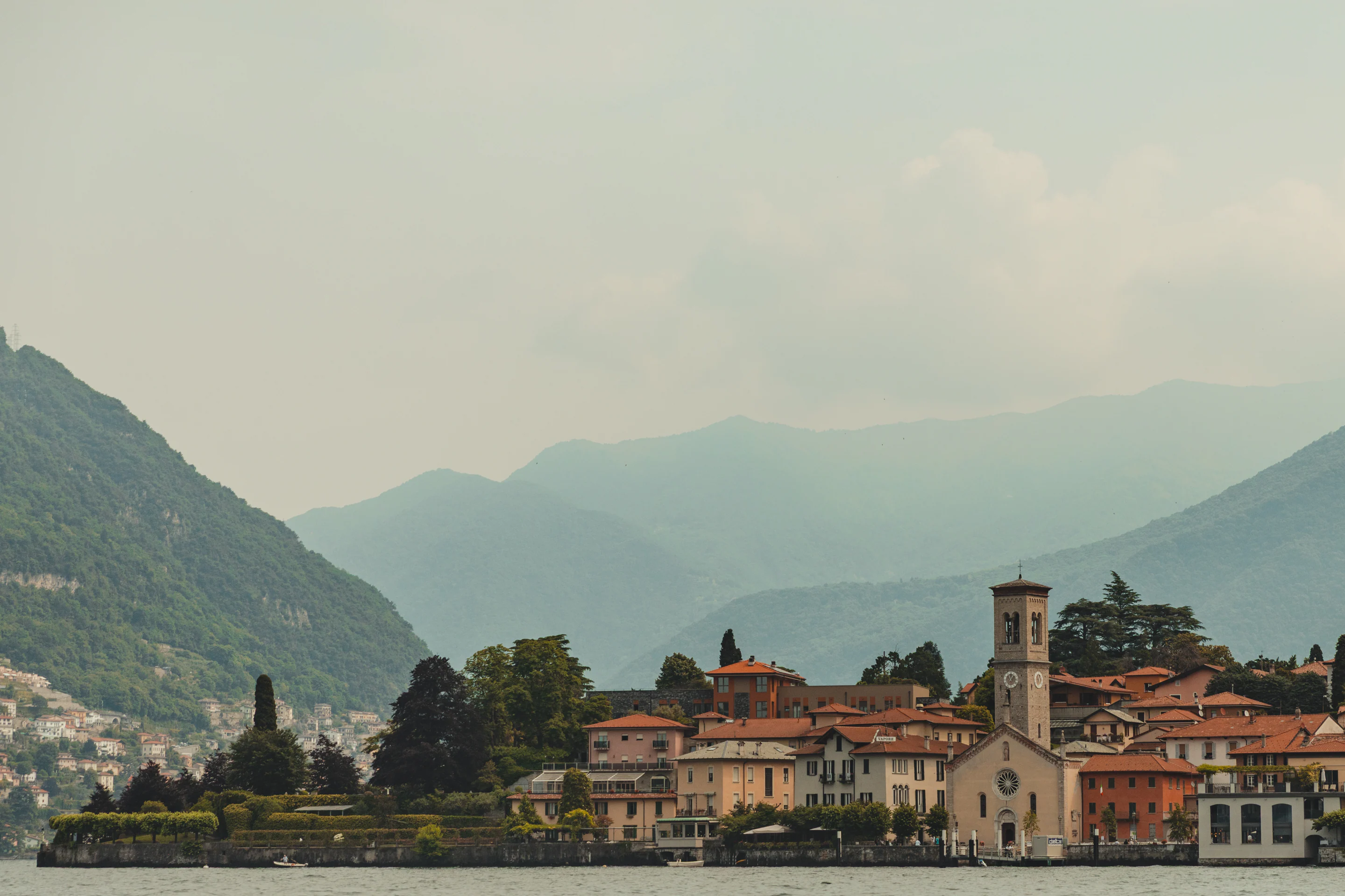 A Lake Como village and church beneath hazy mountains