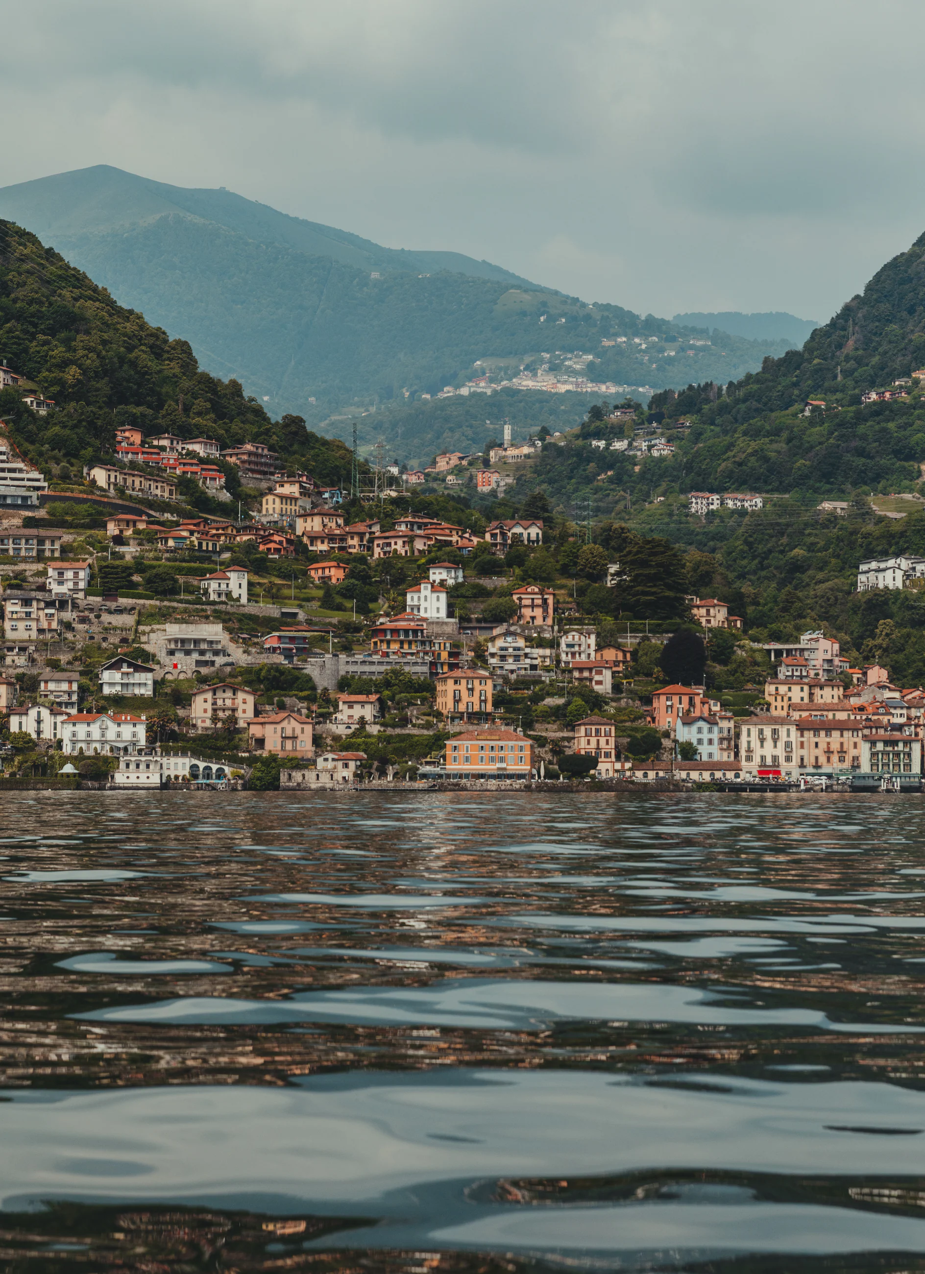 Lake Como water reflecting a town climbing the hillside