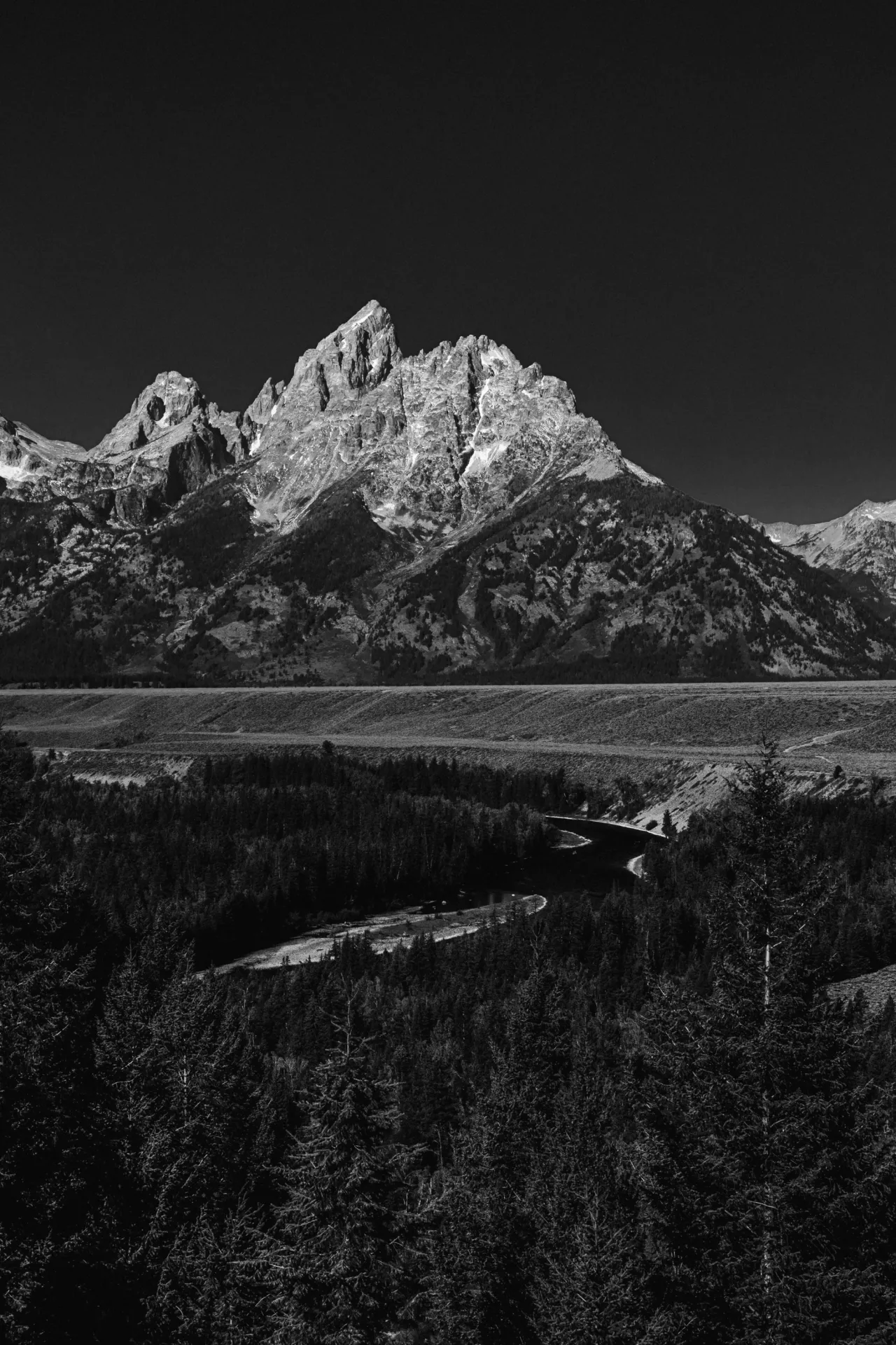 Black-and-white photograph of the Snake River beneath the Teton Range